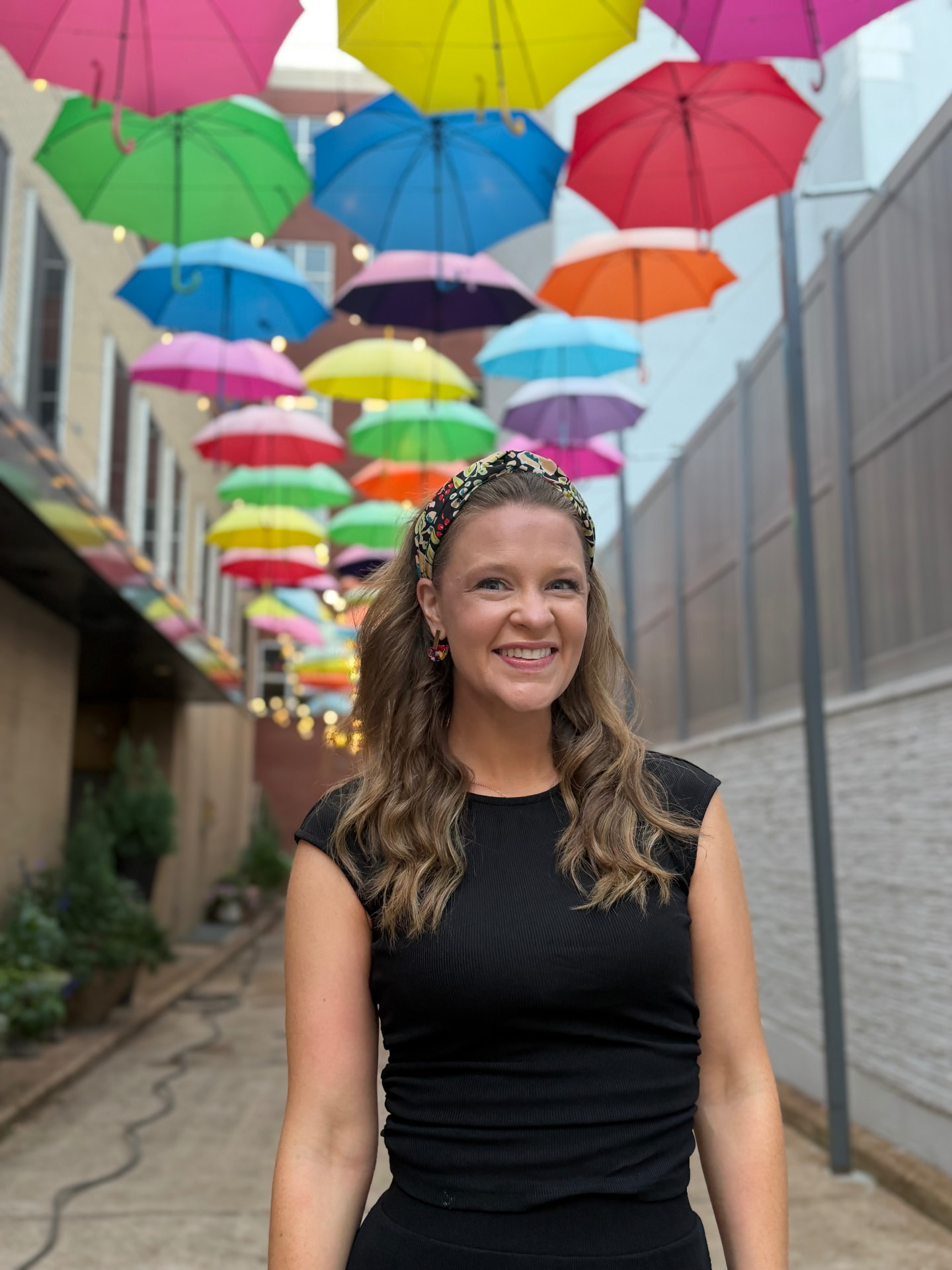 Emily C. Davis smiling beneath a canopy of colorful umbrellas